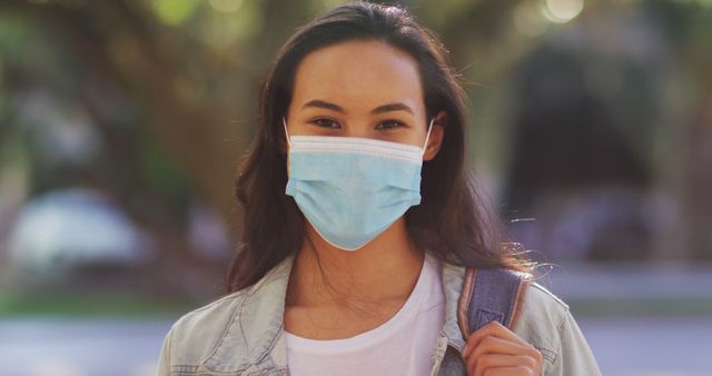 Portrait of asian woman wearing face mask with backpack standing on the road. coronavirus covid-19 pandemic concept