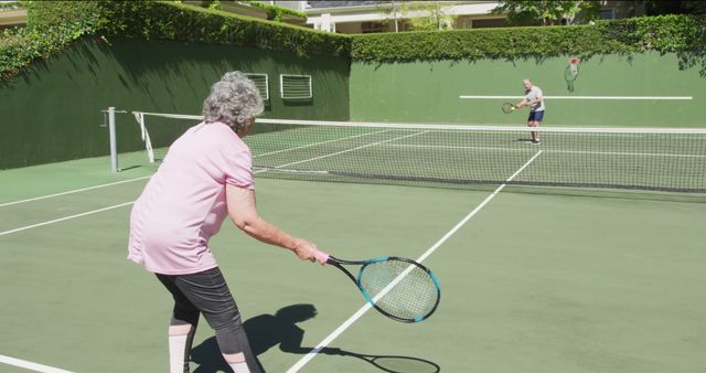 Caucasian senior couple paying a game of tennis on an outdoor court in the sun. active retirement lifestyle sports hobby.