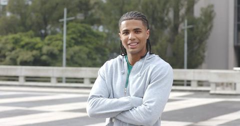 Confident African American man standing with arms crossed smiling in urban plaza