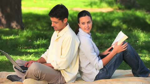 Couple Relaxing Together in Park Leisure Time Technology Books
