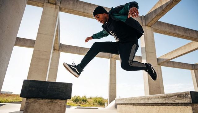 Leaping parkour athlete jumping between concrete platforms beneath urban frames