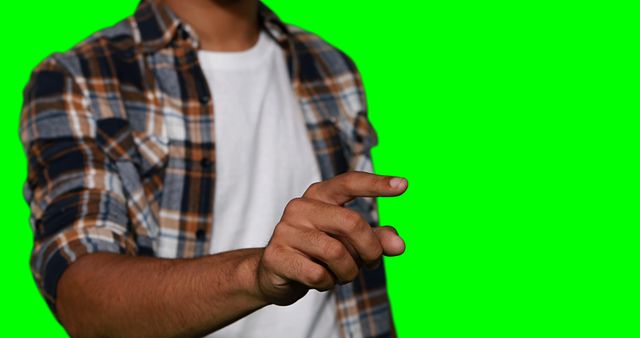 Person wearing plaid shirt using finger to point on green screen background. Suitable for promotional materials, technology demonstrations, app interfaces, educational content. Ideal for use in graphics requiring hand interactions or actions.