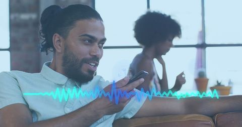 Mixed ethnicity man using smartphone for voice recording in casual office
