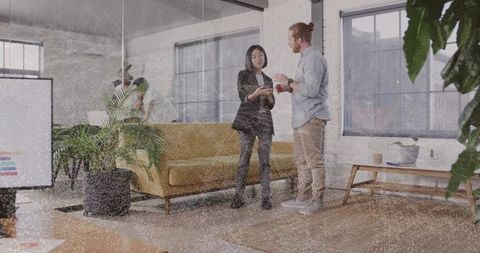 Colleagues discussing in modern coworking lounge with mustard sofa and plants