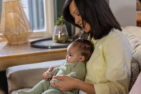 Smiling mother holding baby on sofa creating warm parenting moment