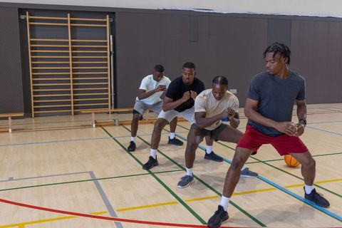 Four african american men practicing lateral footwork and agility on basketball court