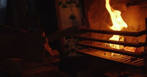 Caucasian Man Adding Wood to Warm Cozy Fireplace