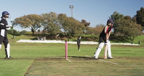 Female Cricketers in Action on Lush Green Field with Pink Stumps