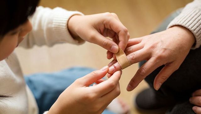 Child Applying Bandage to Adult Finger Close-Up Family First Aid Caregiving Intimate Moment