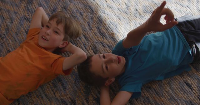 Two Boys Lying on Carpet Pointing and Smiling - Download Free Stock Images Pikwizard.com