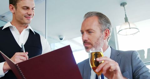 Businessman ordering drink from waiter in modern restaurant