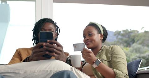 African American Couple Shopping Online on Sofa with Credit Card and Smartphone