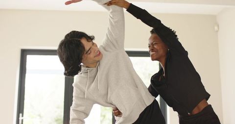 Young couple stretching together during bright home workout session by large windows
