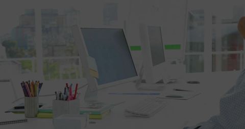 Modern coworking workstation showcasing dual monitors, keyboard, stationery and city view