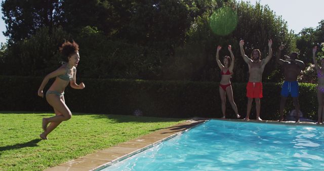 Diverse group of friends having fun jumping into a swimming pool. hanging out and relaxing outdoors in summer.