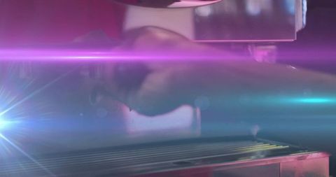 Male worker operating horizontal metal press with neon light streaks and chrome grate