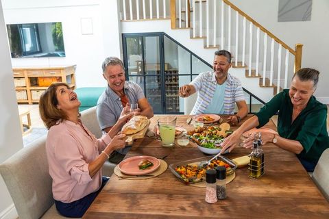 Senior friends sharing lunch at home with joyful conversations
