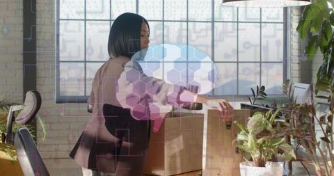 Asian woman unpacking boxes in modern plant-filled loft with digital hexagon brain overlay