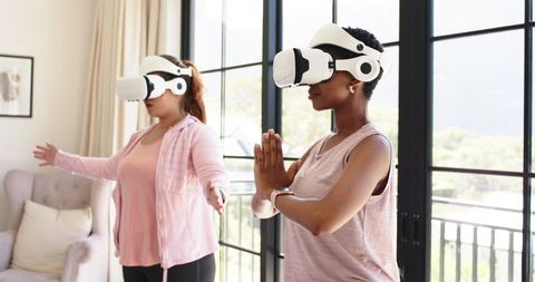 African American Women Practicing VR Meditation and Fitness at Home in Pink Activewear