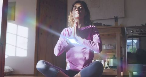 Serene Woman Meditating in Sunlit Room with Lens Flare