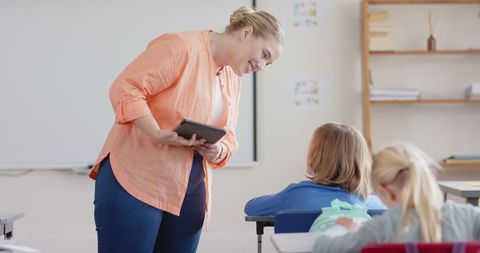 Teacher engaging student with digital learning technology in classroom