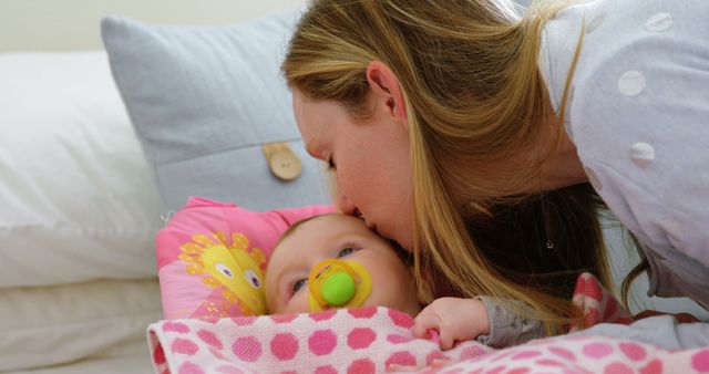 Caucasian woman kisses her baby at home. A tender moment of motherhood is captured as she comforts her child.