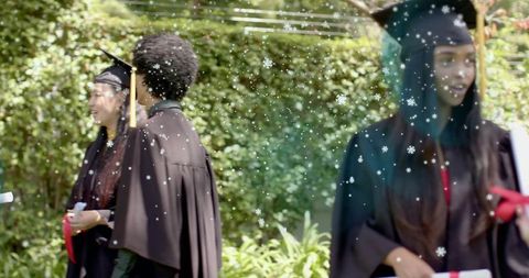 Graduates wearing caps and gowns celebrating outdoors with snowflake overlay