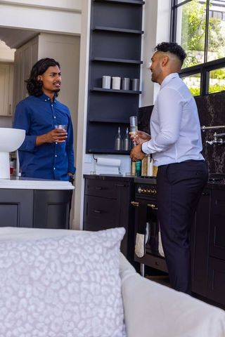 African american men having casual conversation in modern sunlit open-plan kitchen