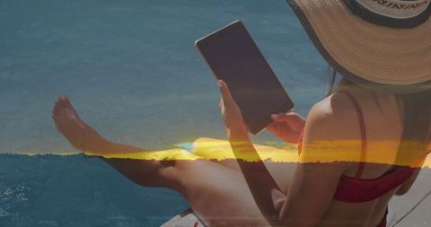 Leisurely Woman in Sunhat Relaxing by Pool with Tablet