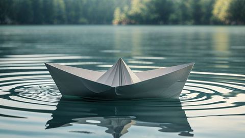Serene paper boat floating on calm lake