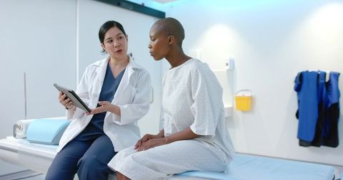 Diverse Female Clinician Consulting Patient with Tablet in Modern Medical Exam Room