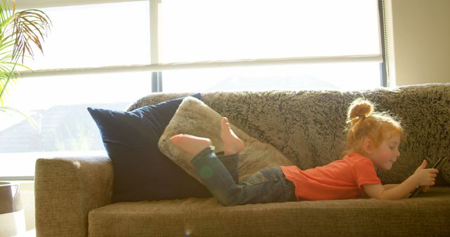 Happy Child Relaxing on Sofa with Tablet in Sunny Living Room - Download Free Stock Images Pikwizard.com