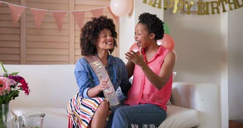 Joyful Female Couple Celebrating Birthday with Happy Banner and Balloons
