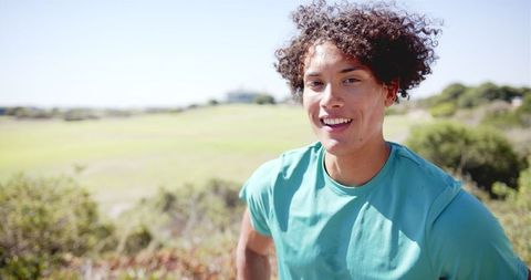 Energetic young adult with curly hair enjoying sunny day outdoors
