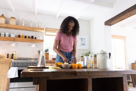 African american woman slicing oranges on rustic farmhouse kitchen island preparing fresh citrus