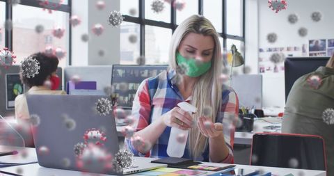 Woman in office disinfecting hands surrounded by virus imagery