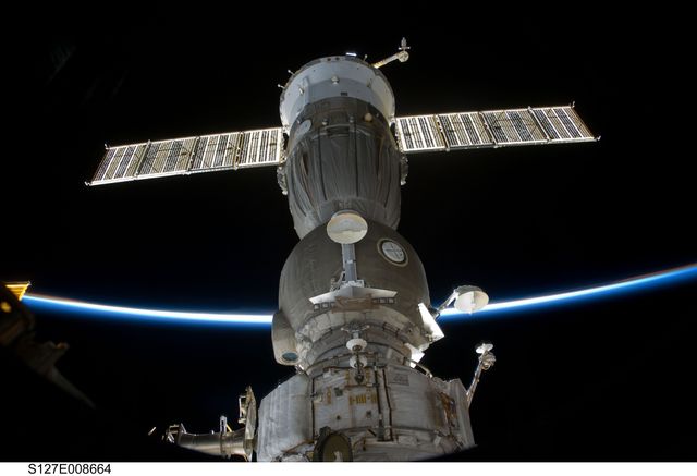 This image showcases the Soyuz spacecraft docked at the International Space Station with the stunning backdrop of Earth's limb. The photo encapsulates the grandeur of space exploration and human engineering. It is ideal for use in articles, educational materials, or documentaries about space travel, astronautics, and engineering marvels.