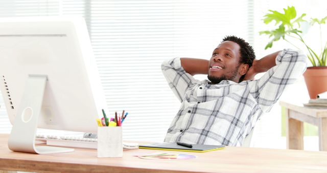 Relaxed professional in modern office leaning back and smiling at desk - Download Free Stock Images Pikwizard.com