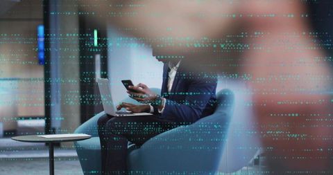 Executive working on laptop and smartphone in modern lounge with teal data overlay