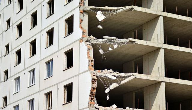 Partially demolishing apartment block revealing exposed concrete floors and rebar