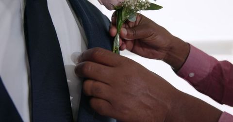Groom adjusting boutonniere for wedding ceremony celebration