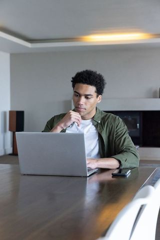 Focused Young Man Working on Laptop in Minimalist Living Room