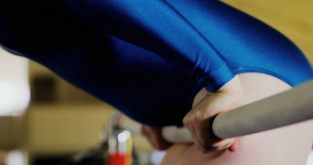 Close-up view of a gymnast gripping the uneven bars during training, showcasing focus and strength. Ideal for use in sports-related articles, fitness blogs, motivational content, and athletic training guides.