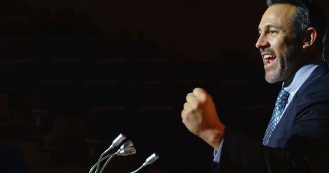 Confident Businessman Delivering Energetic Speech at Podium - Download Free Stock Images Pikwizard.com
