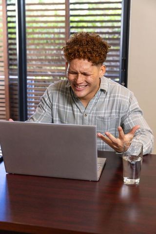 Frustrated man working at laptop in home office