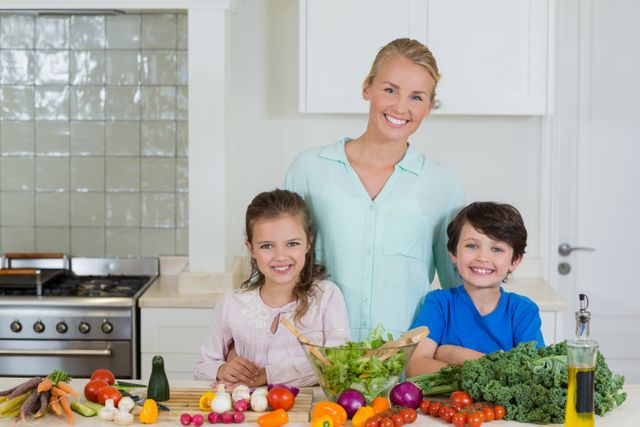 Mother and children smiling while preparing a healthy meal in the kitchen. Fresh vegetables and ingredients are spread on the counter, indicating a focus on nutrition and family bonding. Ideal for use in articles or advertisements about healthy eating, family activities, cooking at home, and promoting a nutritious lifestyle.