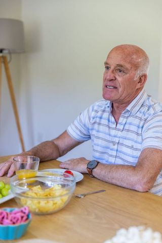 Senior Man Enjoying Breakfast with Orange Juice at Dining Table