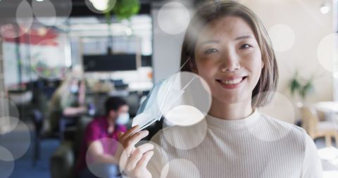 Asian businesswoman smiling while removing face mask in office