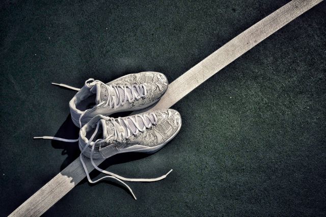 White high-top sneakers lying side by side on a green court line. Suitable for ads focusing on footwear, sports promotions, active lifestyle branding, or casual fashion.