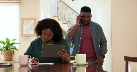 African American Couple Collaborating at Home on Plans with Tablet